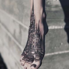 a person's foot with a castle tattoo on it