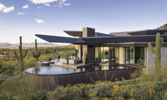 a house with a pool in front of it surrounded by cacti and cactus