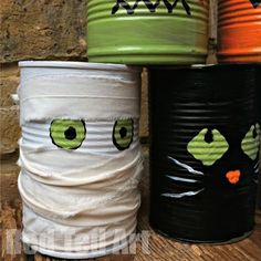 three tin cans with faces painted on them