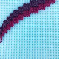 a red and purple piece of yarn sitting on top of a blue surface