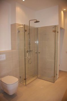 a white toilet sitting next to a shower in a bathroom with beige tile on the walls