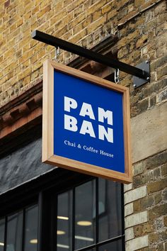 a blue sign hanging from the side of a brick building that says pam and coffee house