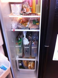 an open refrigerator door with food and drinks in the freezer compartment, including donuts