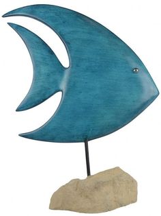 a blue metal fish sculpture sitting on top of a rock