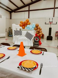 a table set up for a race themed birthday party with balloons and plates on it