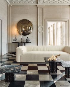 an elegant living room with black and white checkered flooring, large round mirror on the wall