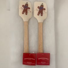 two wooden utensils with teddy bears on them, one is white and the other is red