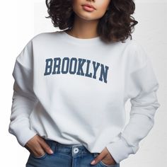 Immerse yourself in the vibrant streets of Brooklyn with our Brooklyn, NY Collegiate Crewneck Sweatshirt. Designed for the urban explorer, this sweatshirt combines polyester's resilience with cotton's softness, ensuring long-lasting comfort and wear. Ideal for a day out in Williamsburg, an evening at a Bushwick gallery, or a morning jog across the Brooklyn Bridge, it keeps you stylish and warm. The ribbed knit collar offers a snug fit that maintains its shape, while the seamless tubular construc Casual Cotton Sweats For Campus, Collegiate French Terry Sweatshirt For Streetwear, French Terry Collegiate Sweatshirt For Streetwear, Cotton Long Sleeve Sweats For Campus, Cotton Sweats For Campus Wear In Fall, French Terry Tops For Fall Streetwear, Varsity French Terry Top For Streetwear, Winter Campus Tops With Text Print, French Terry Crew Neck Top For Streetwear