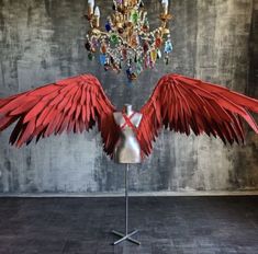 a dress form with red wings and crystal chandelier hanging from it's center