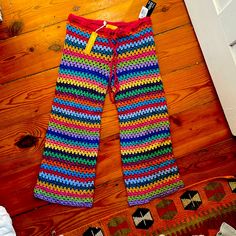 colorful crocheted pants sitting on top of a wooden floor next to a door