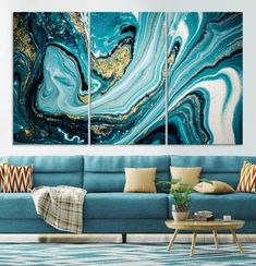 three paintings are hanging on the wall in a living room with blue couches and pillows