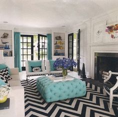 a living room filled with furniture and a fire place covered in blue pillows on top of a black and white rug