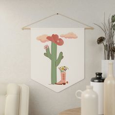 a wall hanging with a cactus and boots on it