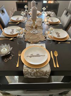 the table is set with gold and white plates, silverware, and candlesticks