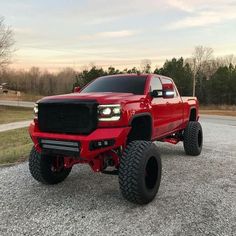 a red truck parked on top of a gravel road