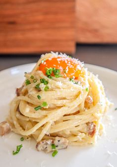 a white plate topped with pasta and an egg on top of it's shell