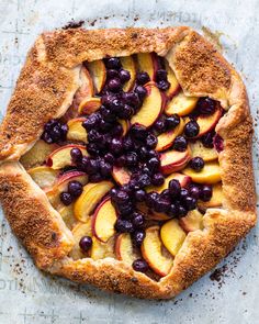 a pie topped with blueberries and peaches on top of a piece of parchment paper