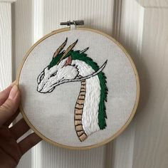 someone is holding up an embroidered dragon head in front of a white door with wood trim