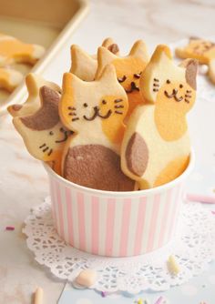 three decorated cookies in a pink and white cup