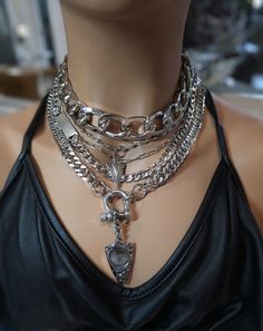 This handmade chunky stainless steel chain layered necklace set is a stunning piece of jewelry that is perfect for those who love bold and edgy accessories. This is two necklaces, the big chunky choker that is adjustable with a built-in extender, and the 4-strand drop festoon design necklace (also adjustable). Adding depth and dimension to the piece is a u lock and arrowhead pendant. Very punk, grunge aesthetic! All the chains are made of sturdy stainless steel, ensuring durability and longevity, and making it completely hypoallergenic, waterproof, and non tarnish. It will look exactly like this forever!  This necklace set is an excellent handmade gift for someone special. It is a perfect choice for those who love alternative and goth styles, as well as anyone who wants to make a statement Goth Layered Necklaces, Silver Accessories Aesthetic, Goth Accessories Jewellery, Choker Necklace Outfit, Punk Grunge Aesthetic, Chains Layered, Edgy Necklace, Chain Layered Necklace, Chunky Silver Necklace