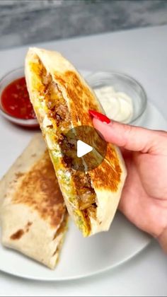 a person is holding a burrito on a plate with sauce and ketchup