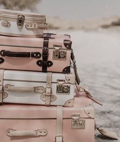 four suitcases stacked on top of each other in front of some sand and trees