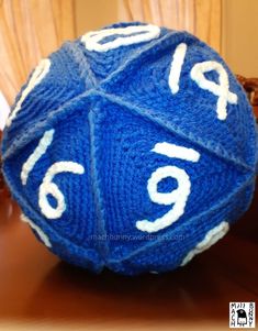 a blue and white knitted ball sitting on top of a wooden table next to a stuffed animal