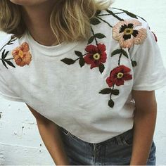 a woman with blonde hair wearing a white t - shirt and floral embroidered flowers on it