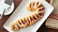 a white plate topped with pastries on top of a wooden table next to a knife and fork