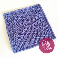 a purple crocheted square sitting on top of a white table next to a button