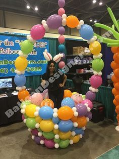 a woman standing in front of a balloon arch with balloons on the top and bottom