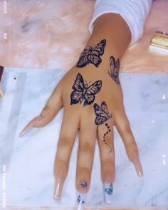 a woman's hand with butterflies painted on it