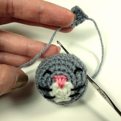 a crocheted cat ornament being worked on by someone's hand