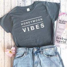 a t - shirt that says honeymoon vibes next to a pair of denim shorts