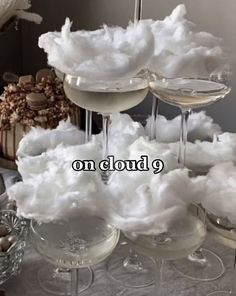 wine glasses filled with white liquid sitting on top of a table covered in cotton balls