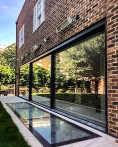 an empty swimming pool in front of a brick building with glass doors on the side