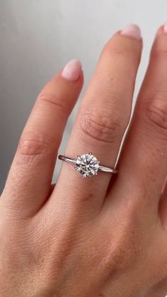 a woman's hand with a diamond ring on top of her finger, showing the center stone