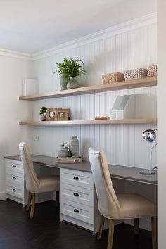 a desk with two chairs and a shelf above it that has some plants on top of it