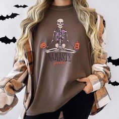 Embrace the spooky spirit with our Namaste Spooky T-Shirt, printed on high-quality Comfort Colors tees. Featuring a skeleton in a meditative pose with jack-o'-lanterns and the phrase "Namaste Spooky," this unique design combines Halloween fun with a touch of zen. Made from 100% ring-spun cotton, this soft and eco-friendly printed shirt is perfect for Halloween parties, yoga sessions, or casual wear. Available in unisex sizes, it's a fantastic addition to any Halloween wardrobe or a unique gift f Spooky Long Sleeve T-shirt With Custom Print, Spooky Custom Print T-shirt For Fall, Pumpkin Tshirt, Comfort Colors Tee, Halloween Skeletons, Halloween Tshirts, Namaste, Comfort Colors, Halloween Party