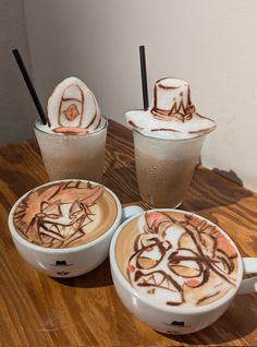 three cups filled with liquid sitting on top of a wooden table next to each other