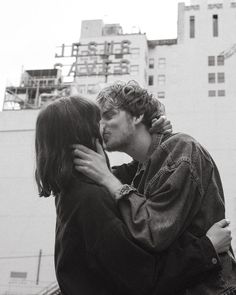 a man and woman embracing each other in front of a tall building with the words love on it