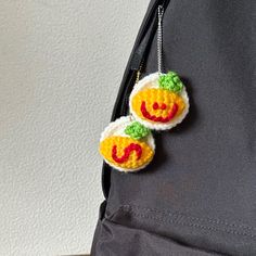 two crocheted pumpkins are attached to a backpack