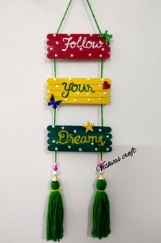 a wooden sign hanging from the side of a wall with tassels on it