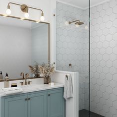 a bathroom with a large mirror and blue vanity cabinets in front of the shower door