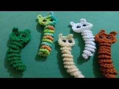 four crocheted animals are lined up on a green surface, one is white and the other is orange