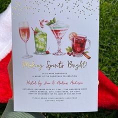 a hand holding up a christmas card with drinks on it and candy canes in the background