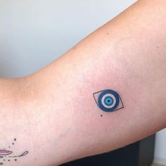 a person's arm with an evil eye tattoo on it