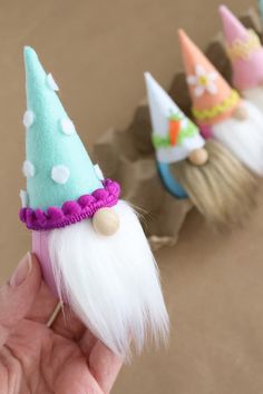 three small gnomes with white hair and green hats on their heads are being held by someone's hand