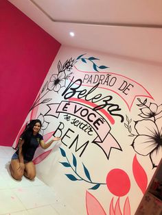 a woman sitting on the floor in front of a wall with flowers painted on it