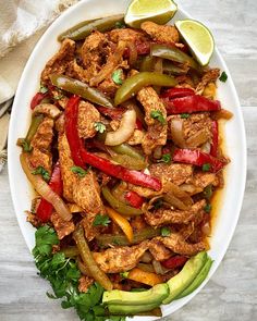 a white plate topped with meat and veggies next to a tortilla